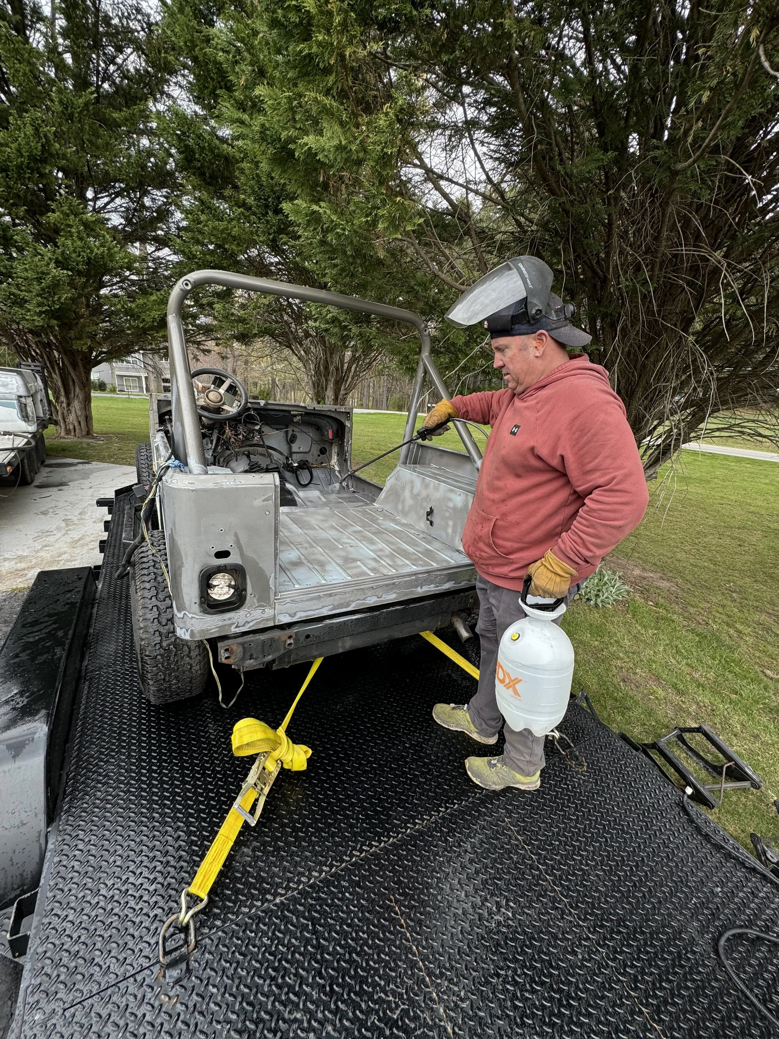 A man welding a vehicle on a trailer