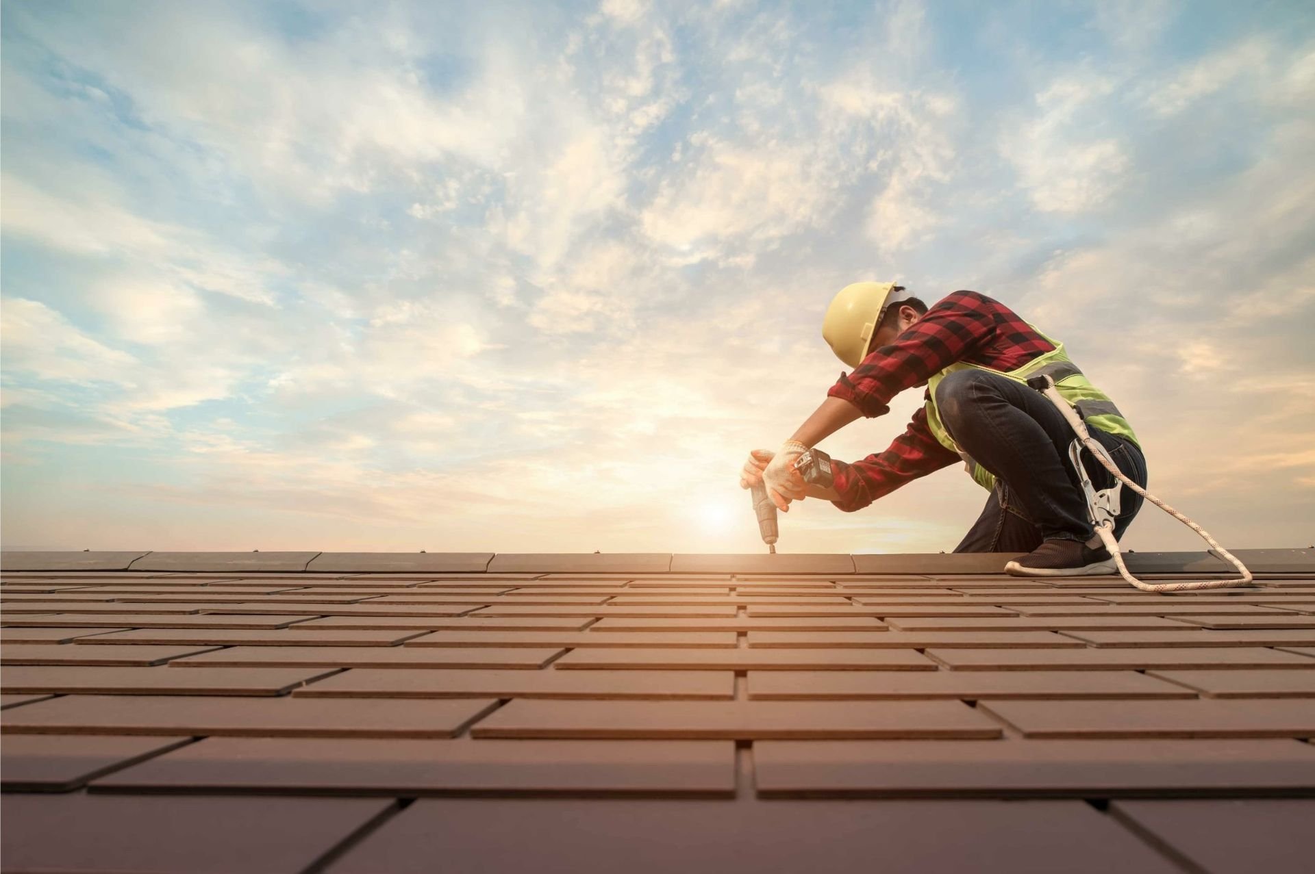 A roofer working on a roof at sunset