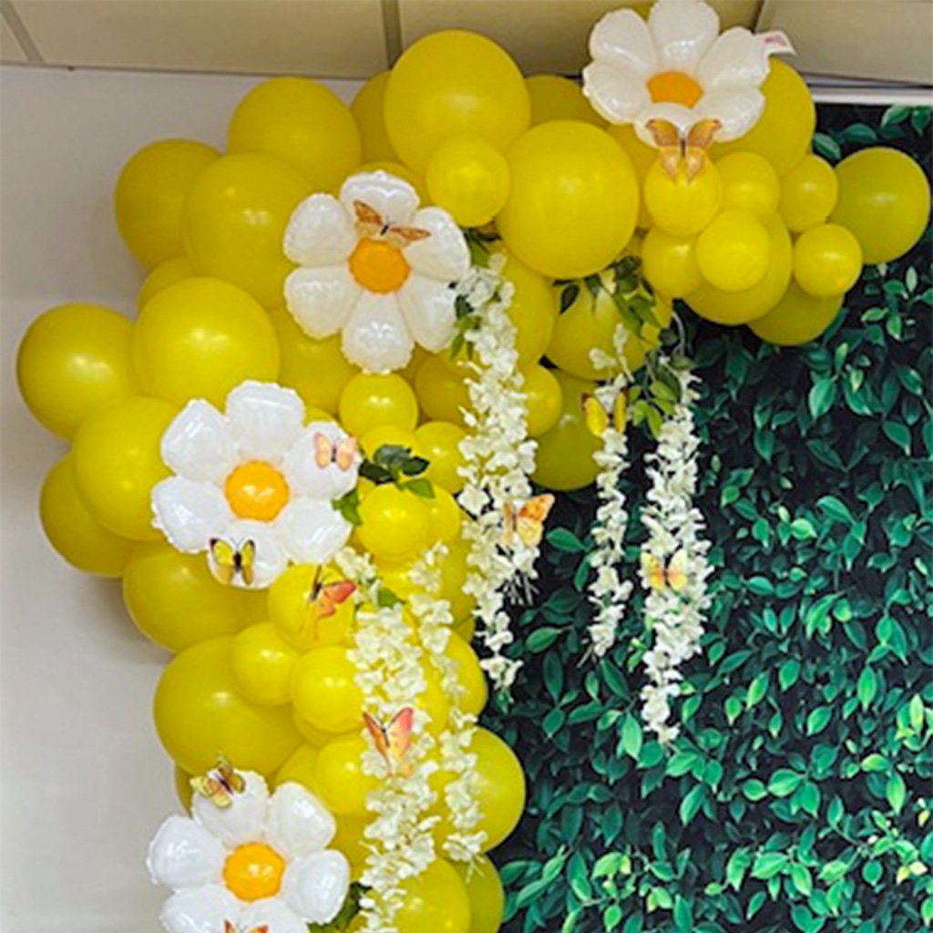A vibrant yellow balloon arch with white flowers and butterflies