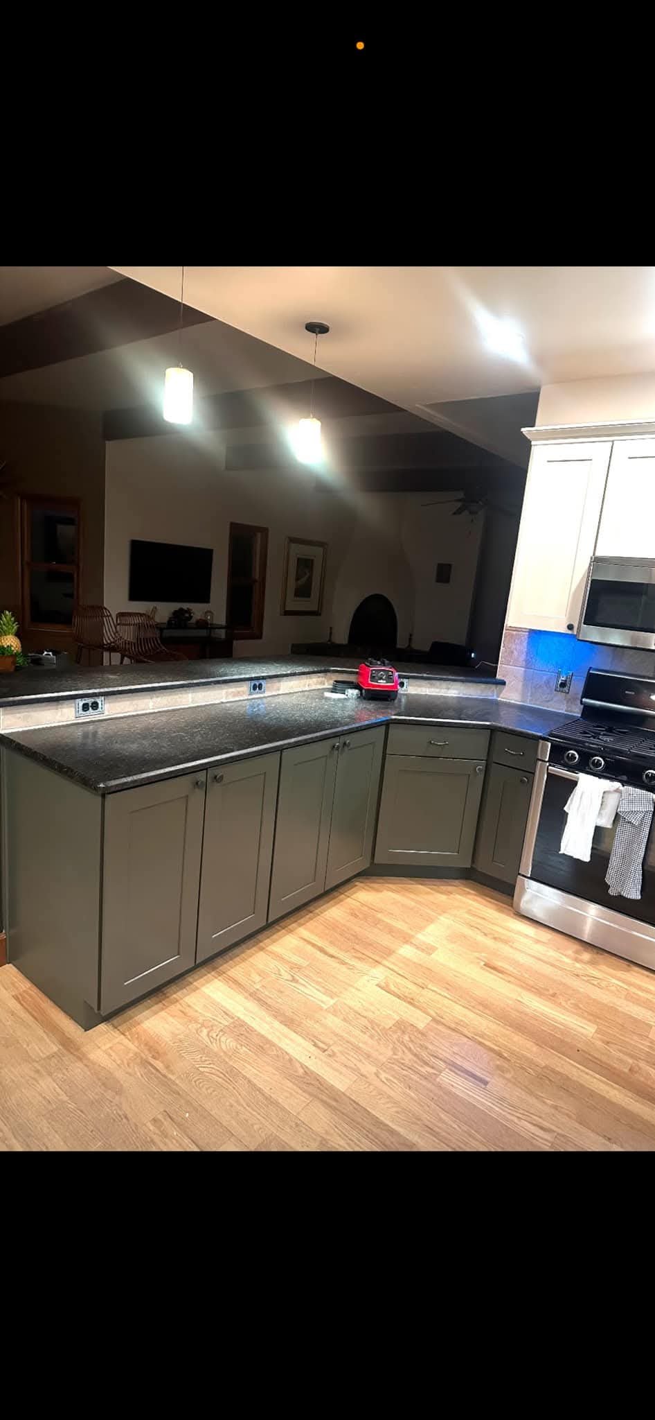A modern kitchen with a large island, black countertops, and gray cabinets.