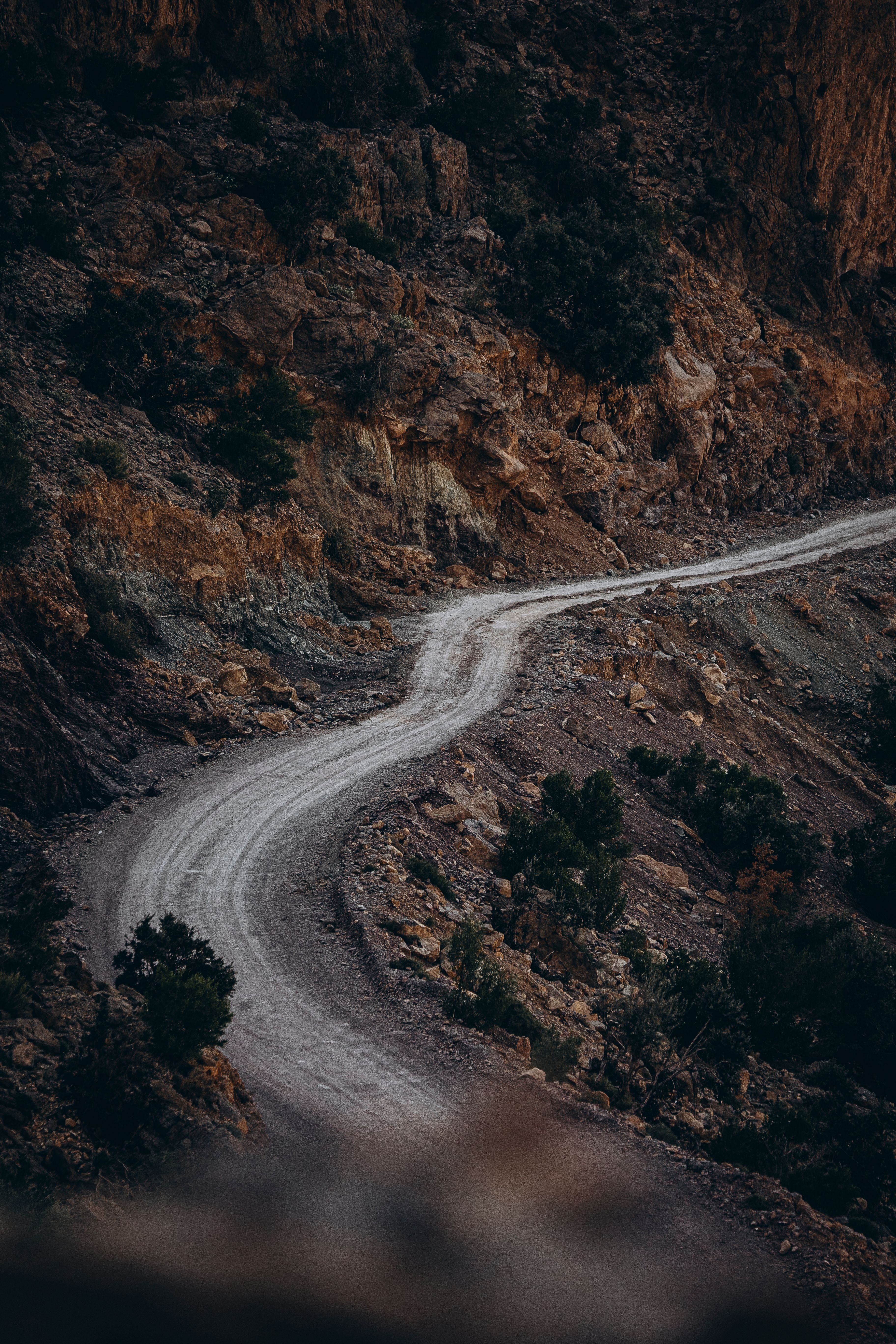 A winding dirt road through a rocky mountain landscape with sparse vegetation