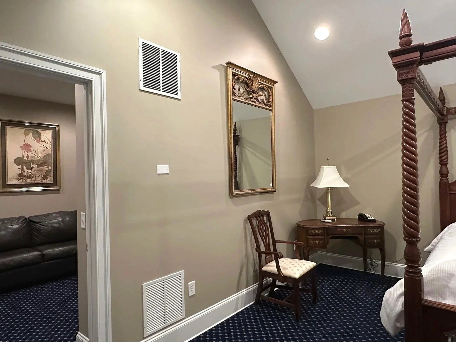 A luxurious bedroom with a canopy bed, a desk, and a couch in the corner