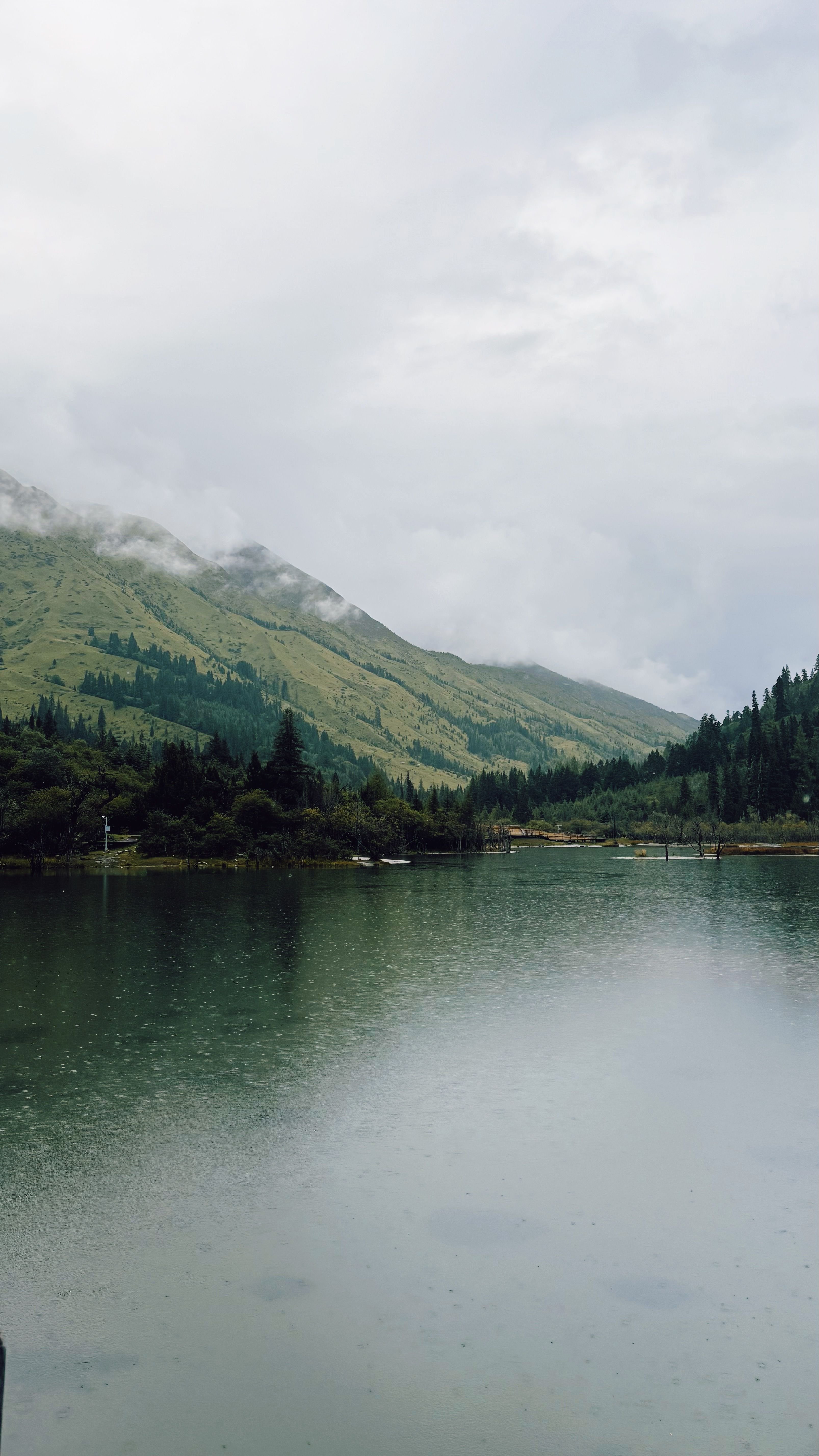 A serene lake with a mountain range in the background under a cloudy sky