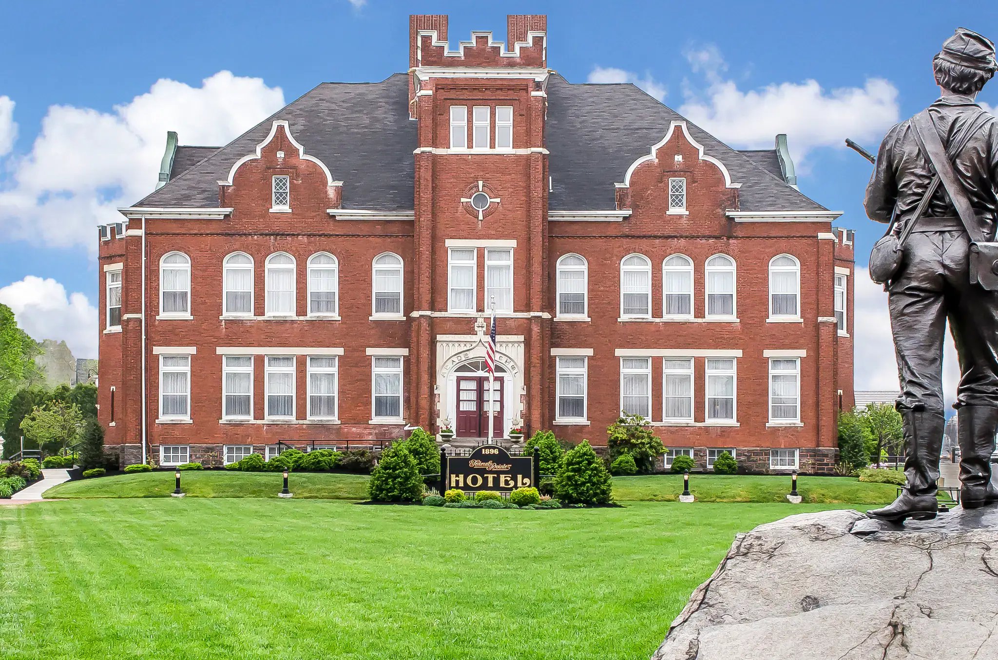 A red brick building with a statue of a soldier in front of it.