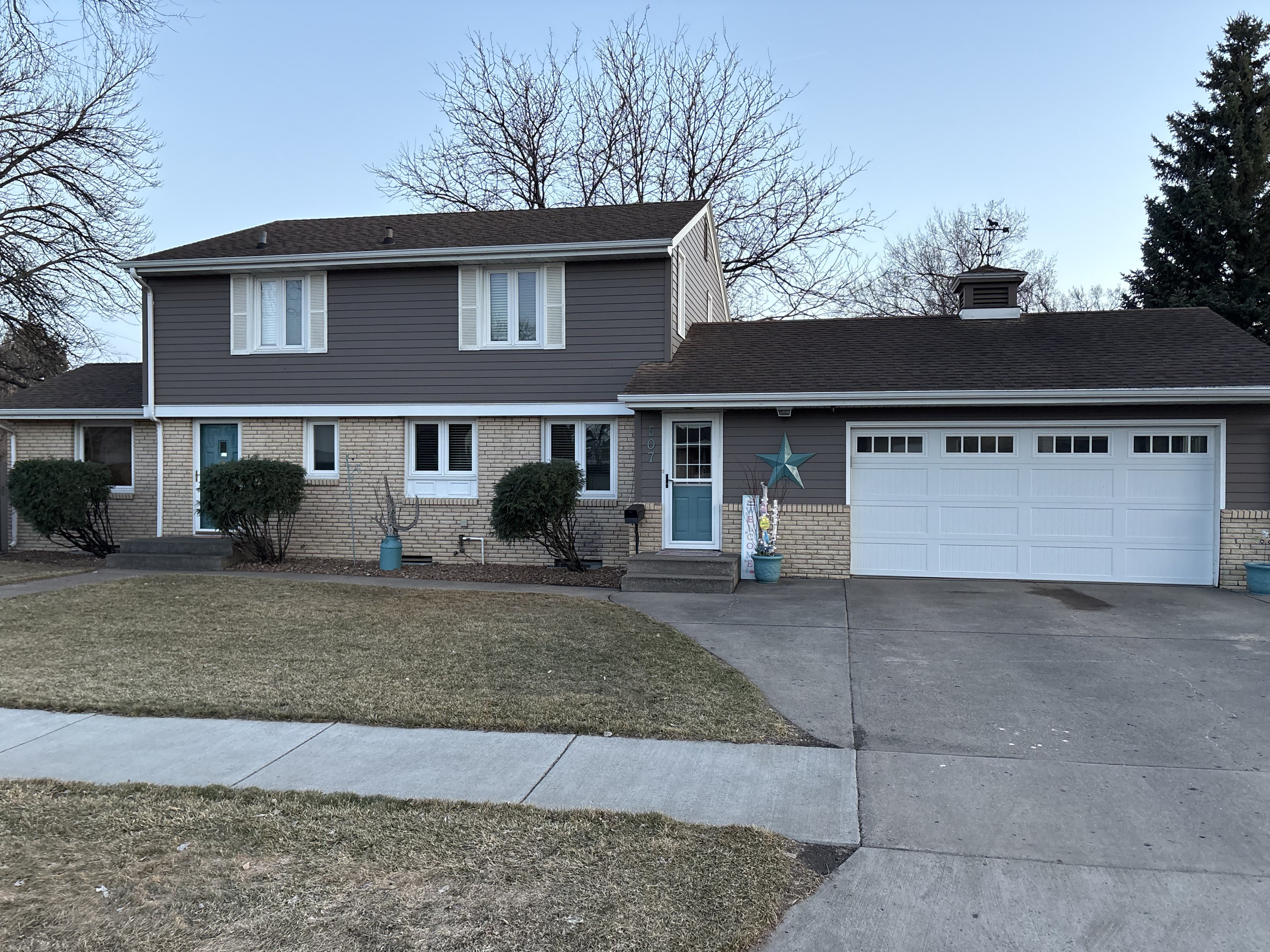 A two-story house with a double garage, teal doors, and a star decoration in front