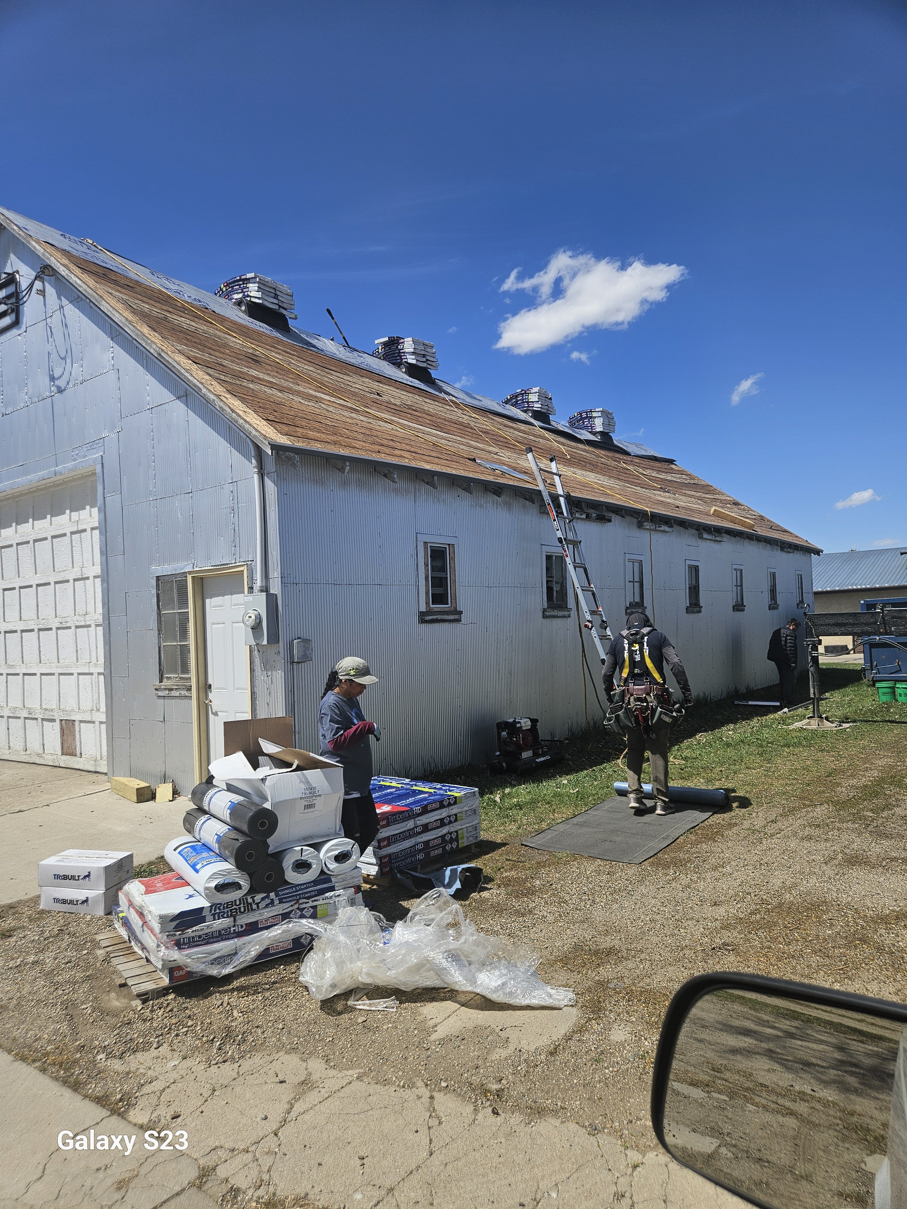 Two workers on a roof with solar panels and materials on the ground