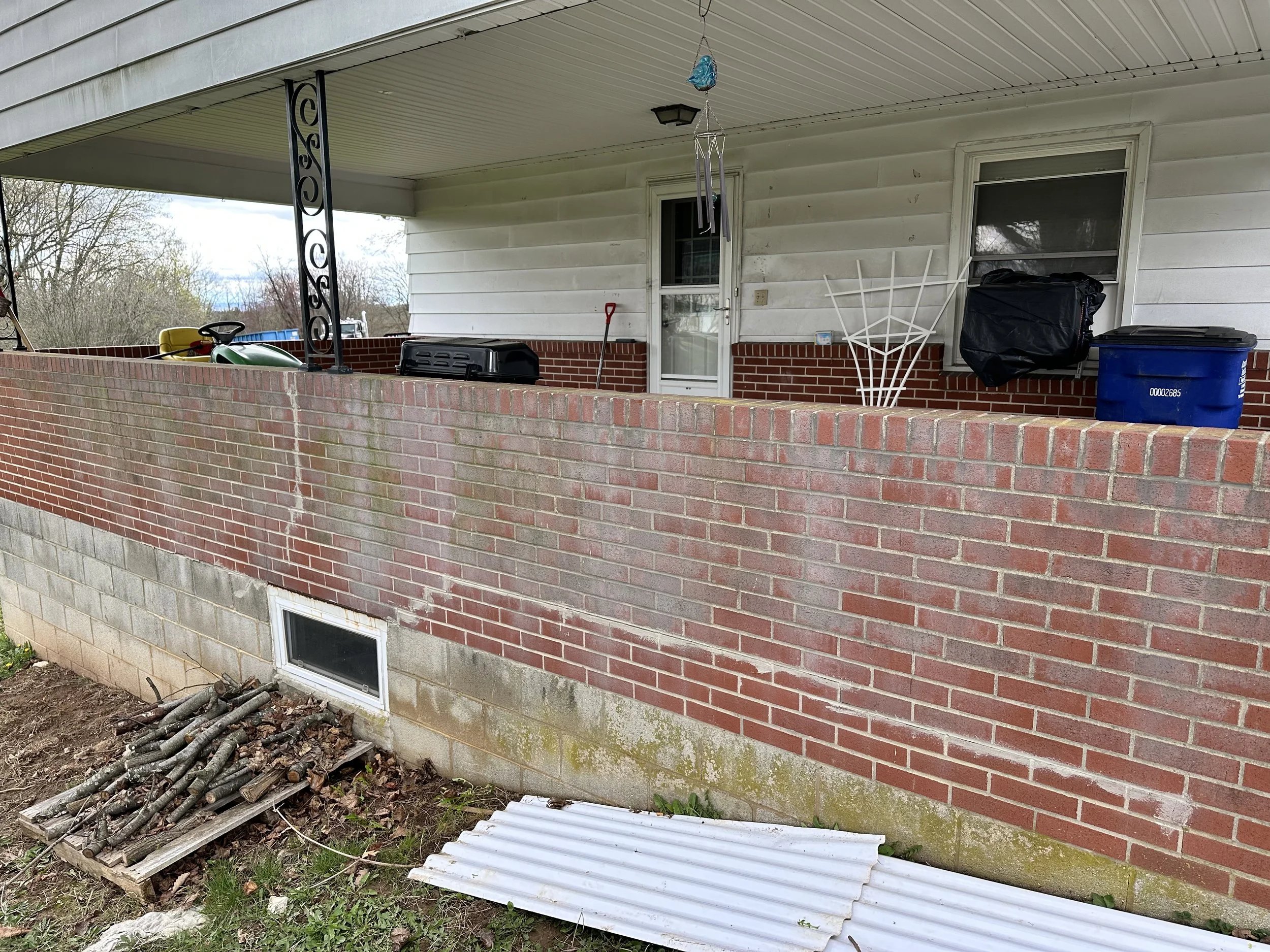A brick wall with a green stain being treated