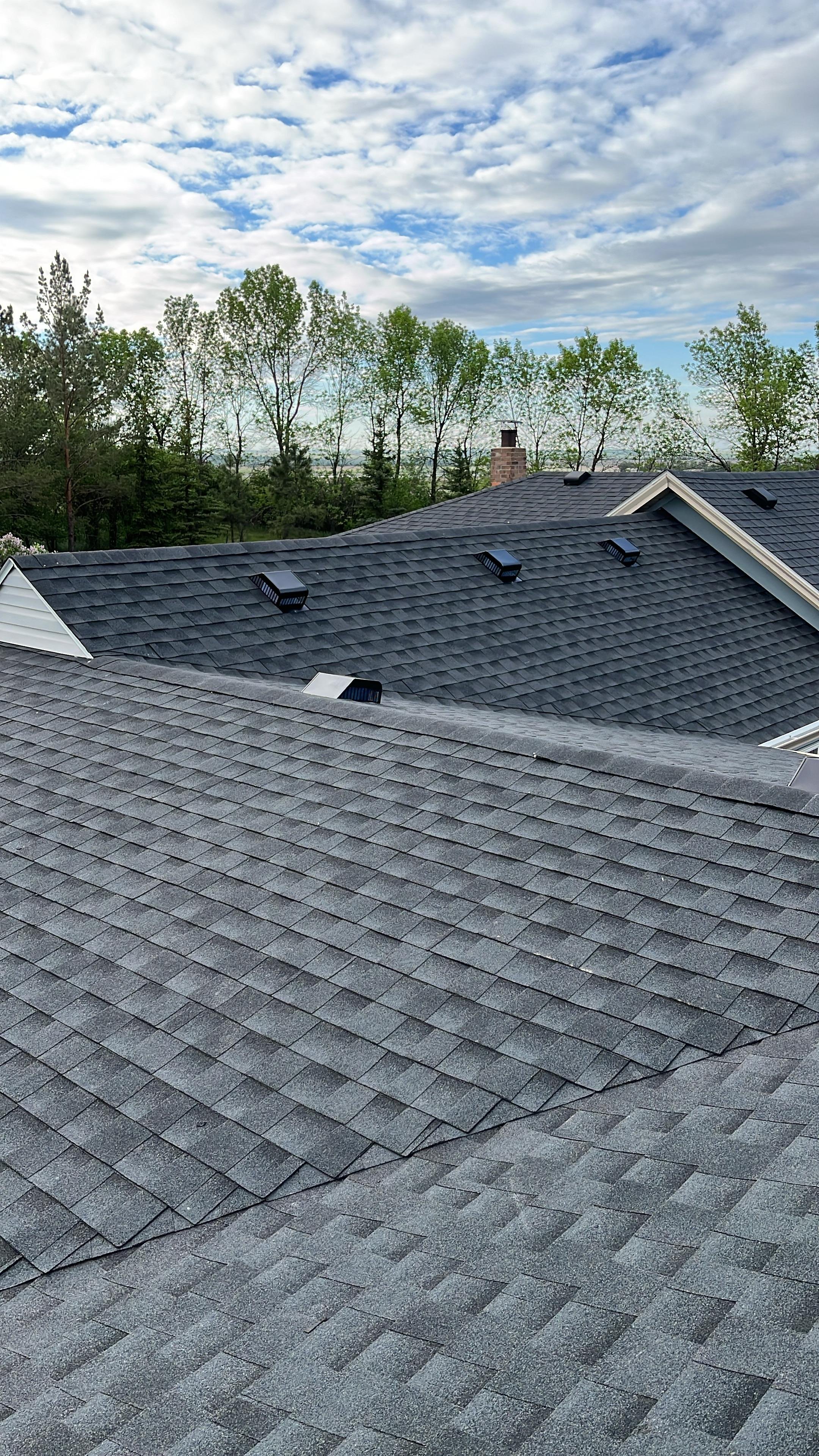 Aerial view of a house with a gray shingled roof and a chimney