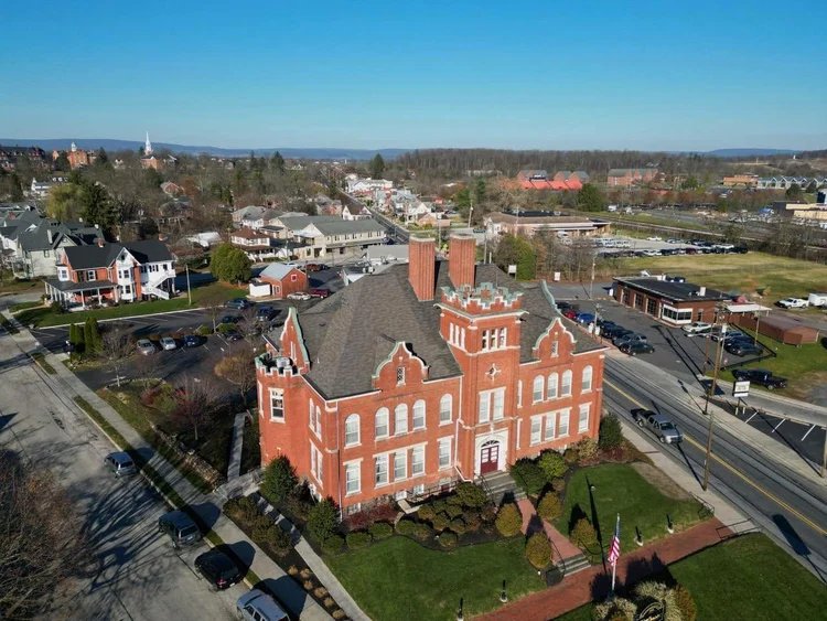 Aerial view of a town with a large red brick building and several cars parked