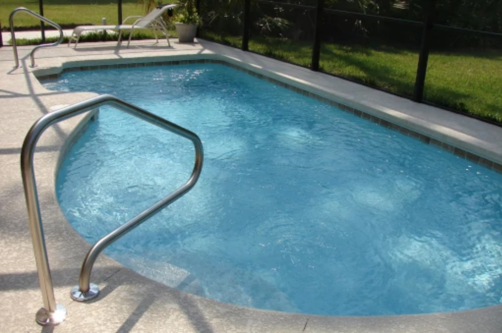 An outdoor swimming pool with a stainless steel handrail and a black fence