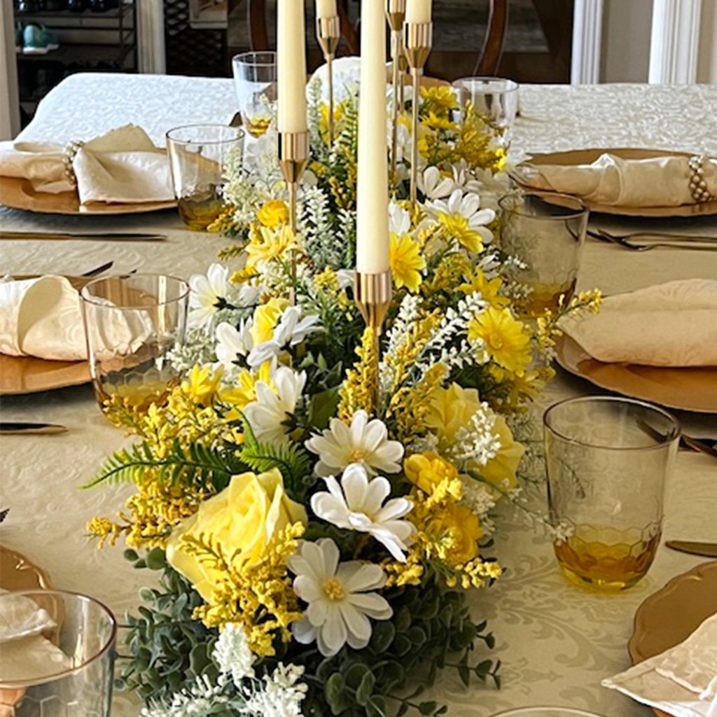 A dining table with a flower centerpiece and candles, set for a meal