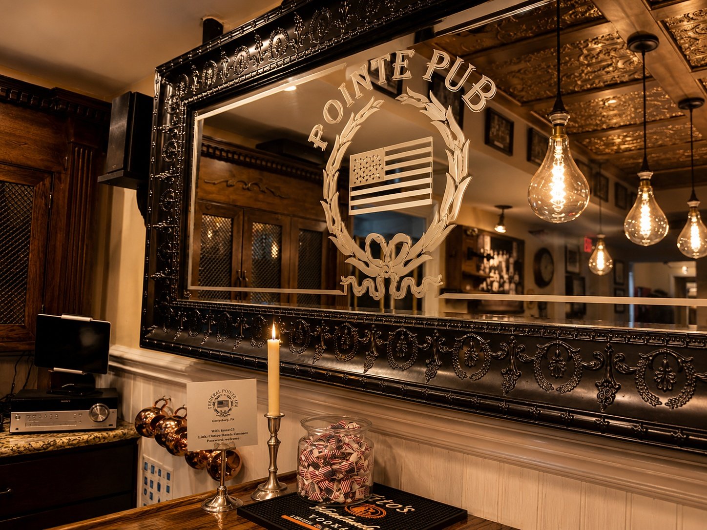 A bar counter with a large mirror displaying the Pointe Pub logo and an American flag