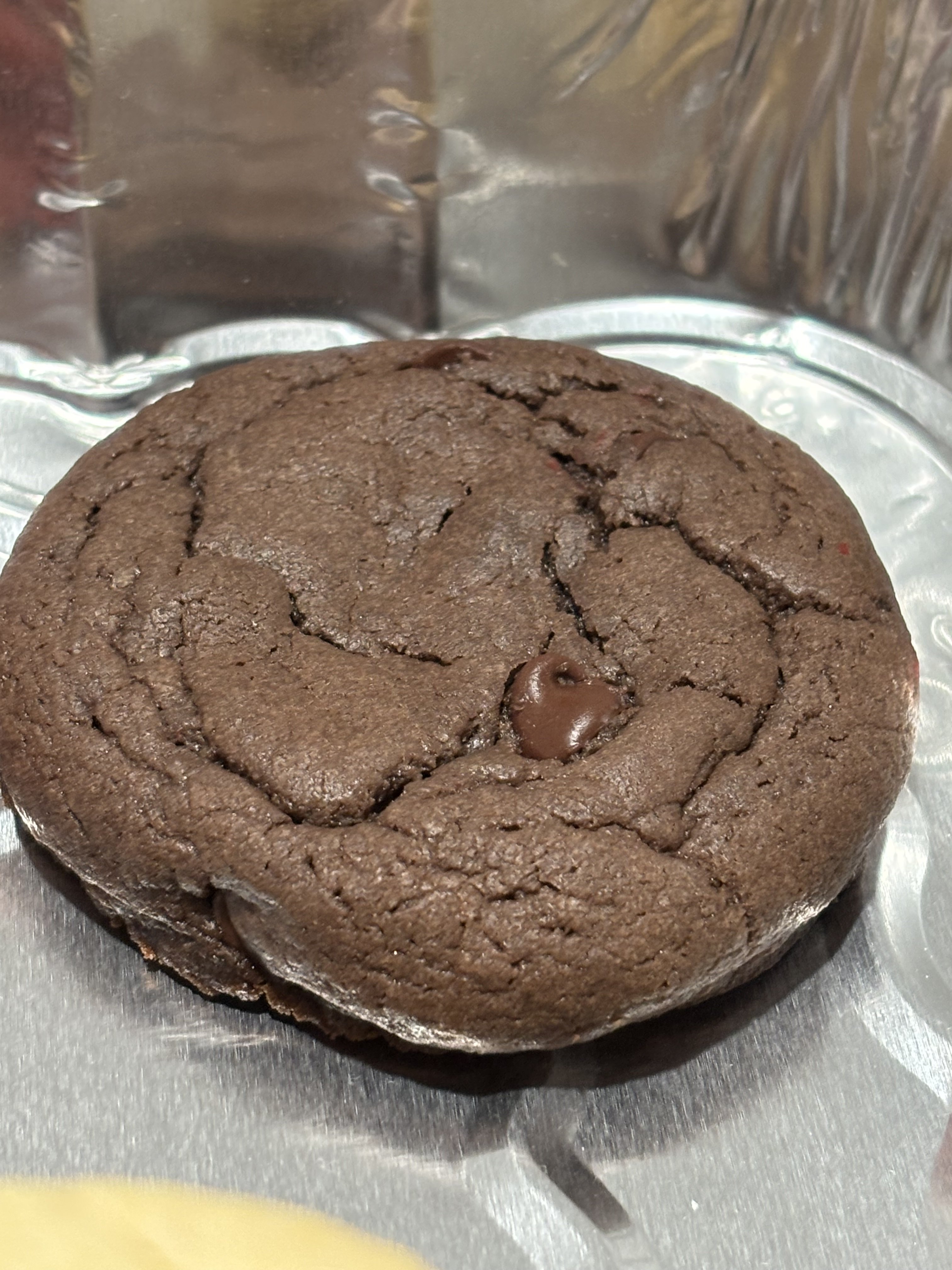 A close-up of a rich, dark chocolate cookie with visible chocolate chips.