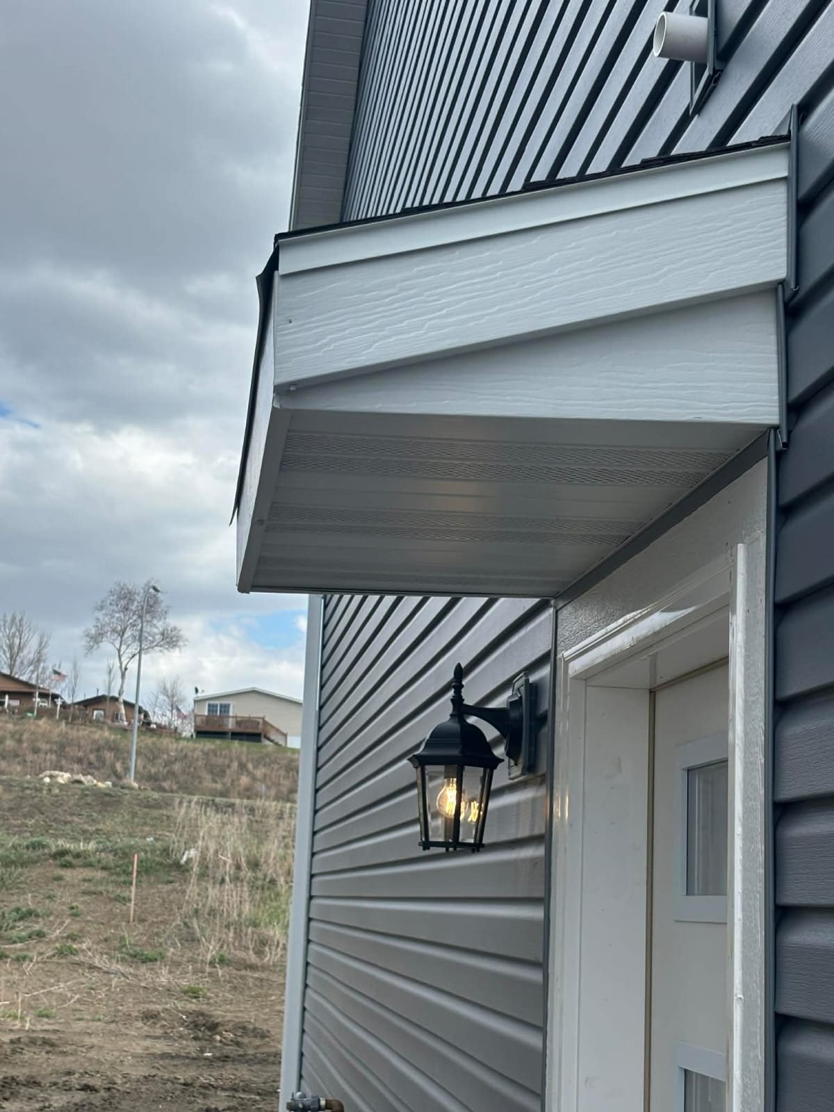 Exterior of a modern house with a gray roof, white door, and a black lantern