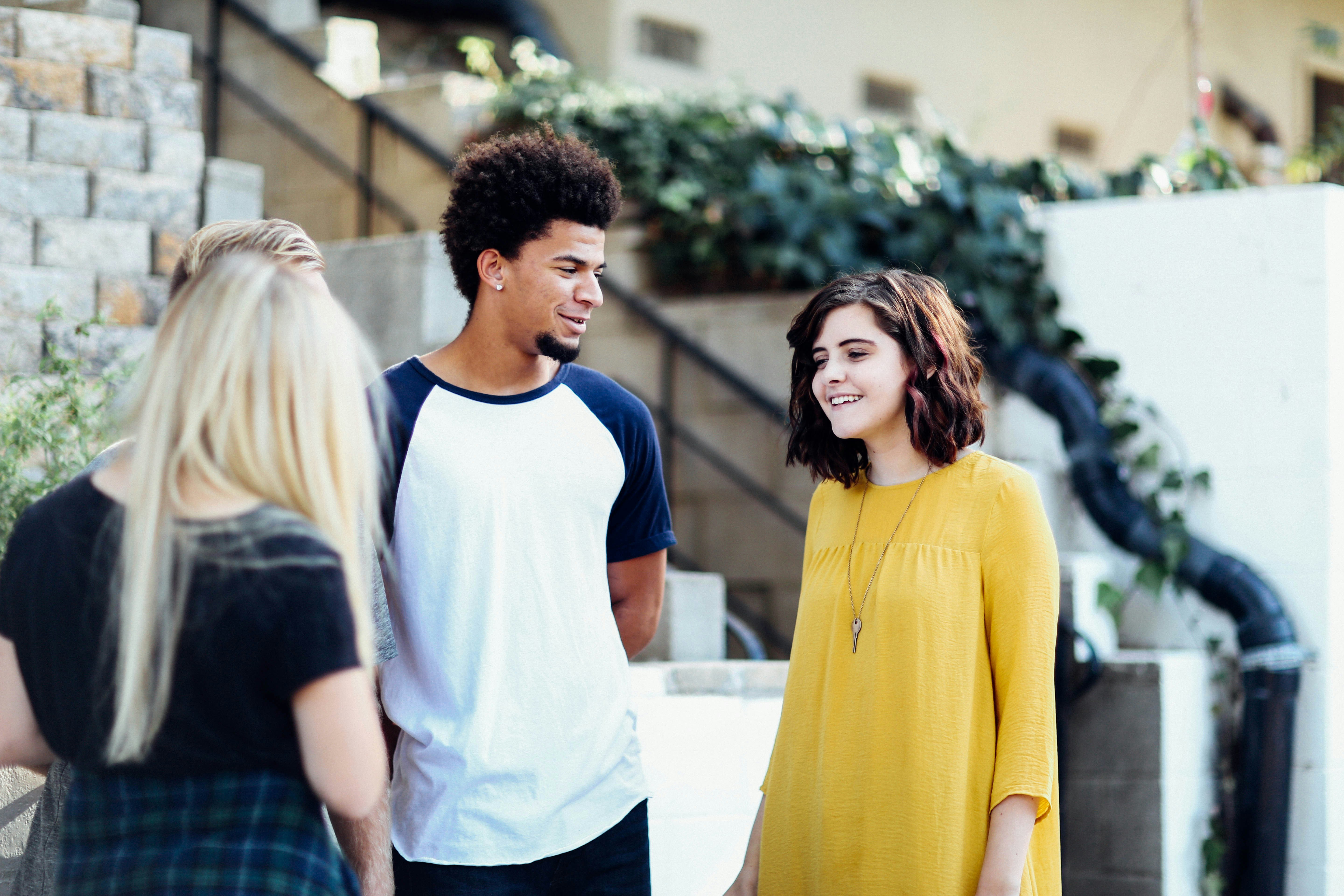 A group of young adults standing outside and smiling at each other