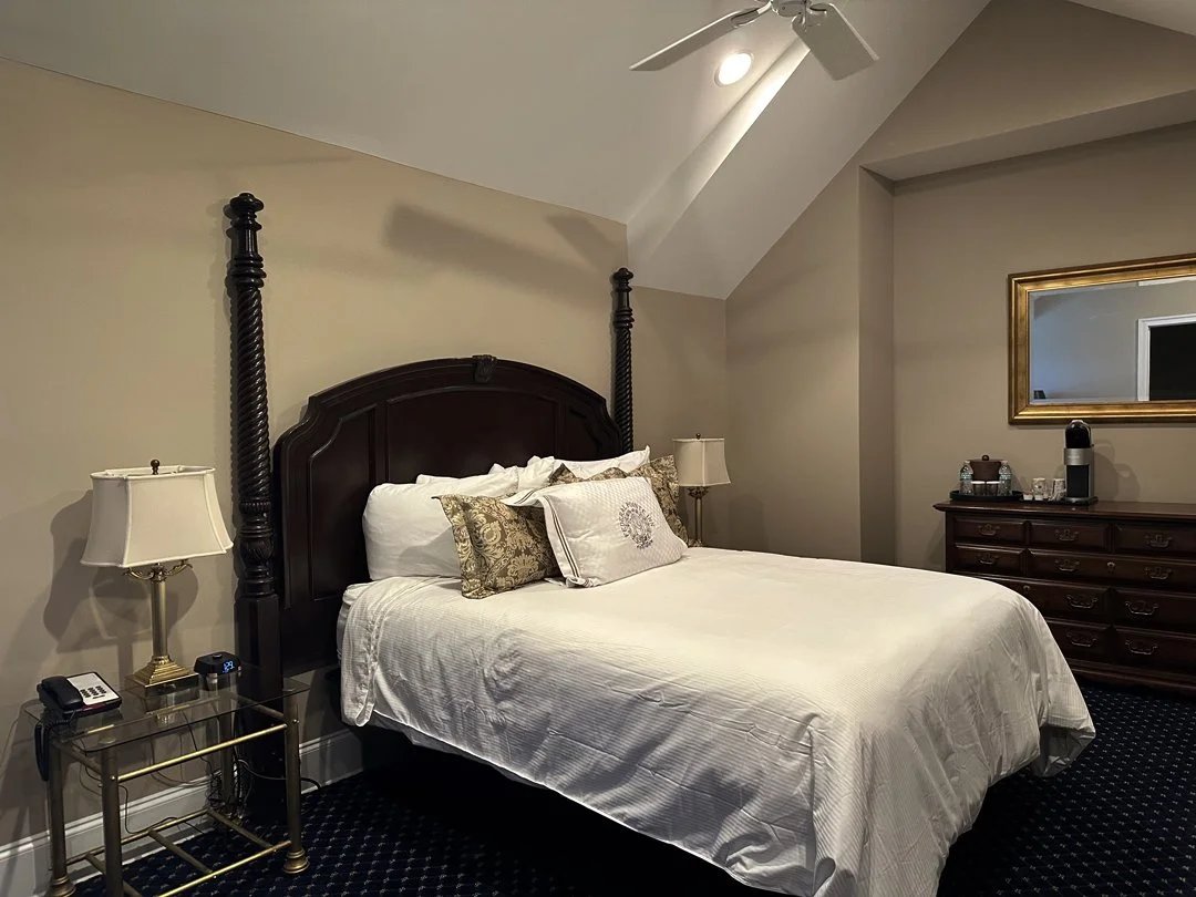 A luxurious bedroom with a bed, nightstands, and a dresser in a hotel room