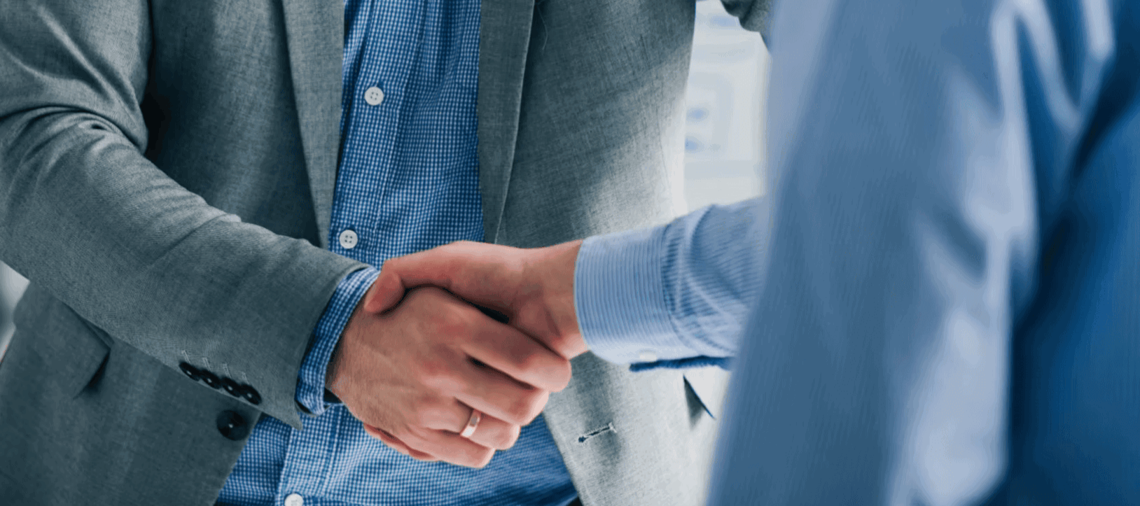 Two men in business attire shaking hands in a professional setting