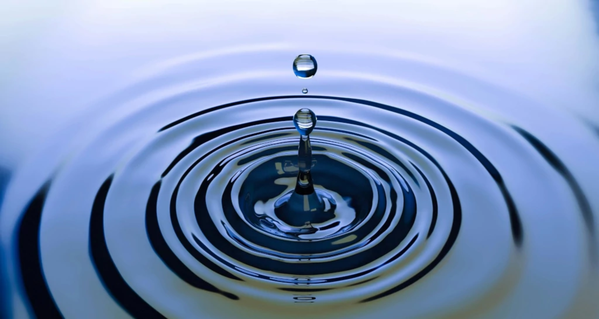A water droplet falling into a pool creating ripples