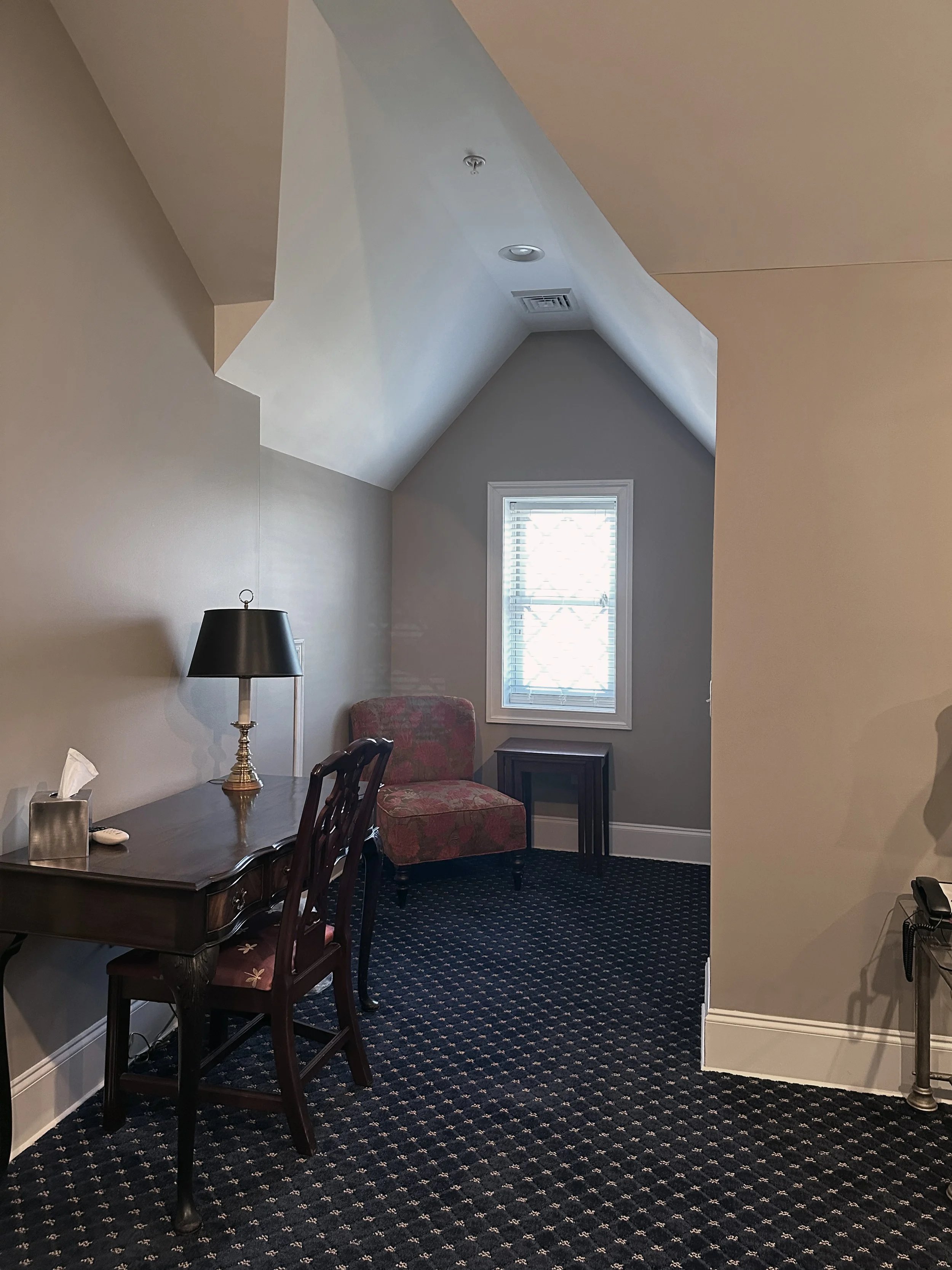 A small, cozy office with a desk, chair, and window with blinds