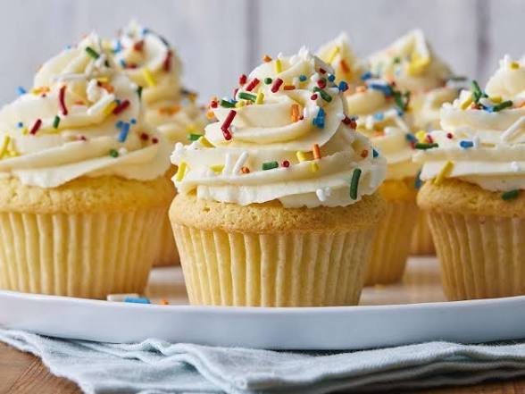 Vanilla cupcakes with white frosting and colorful sprinkles on a white plate