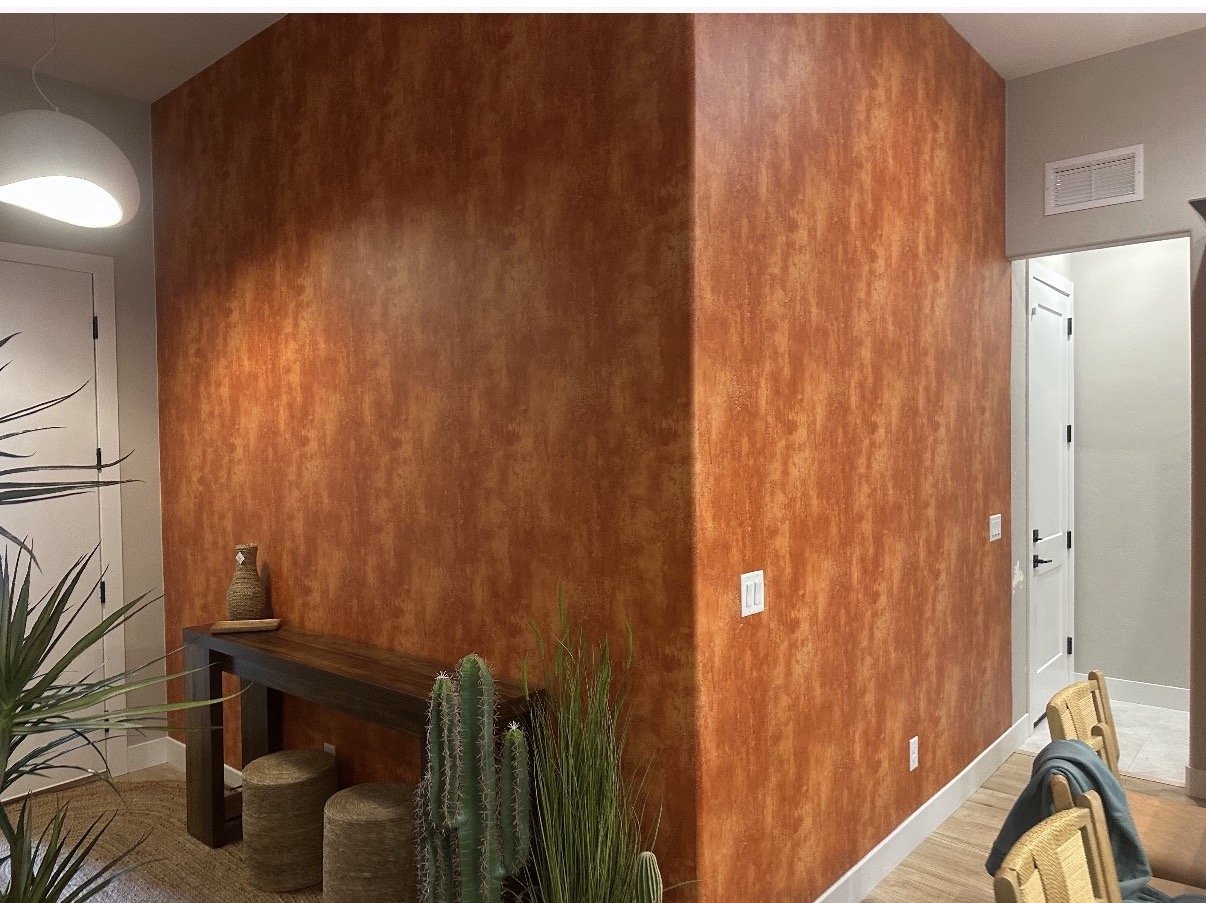 A room with a brown textured wall, a wooden table, and a cactus plant.