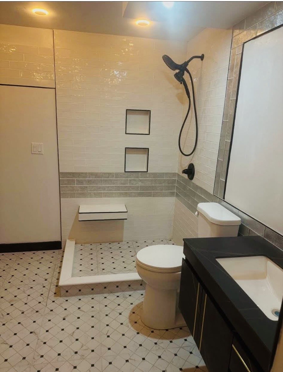 A modern bathroom remodel with white tiles and black accents