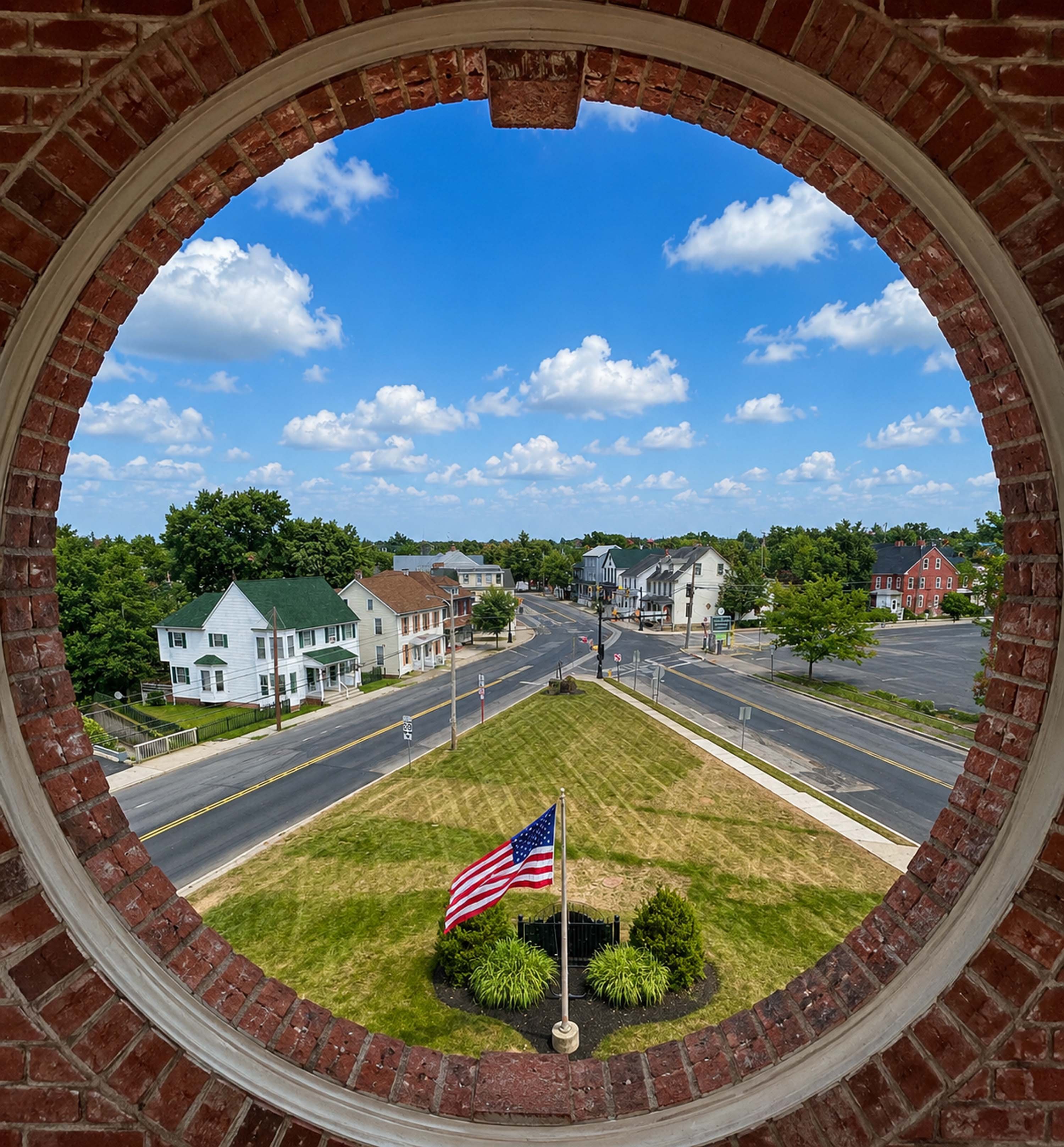 A circular view from a building shows a small town with houses, a flag, and a road.