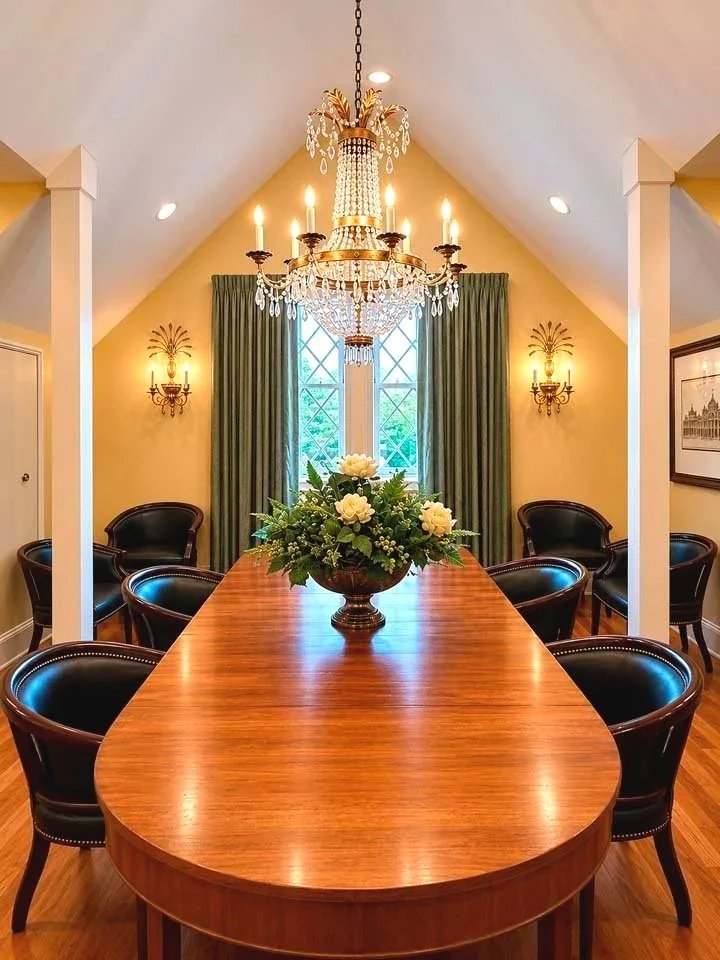 A luxurious dining room with a wooden table, black leather chairs, and a chandelier