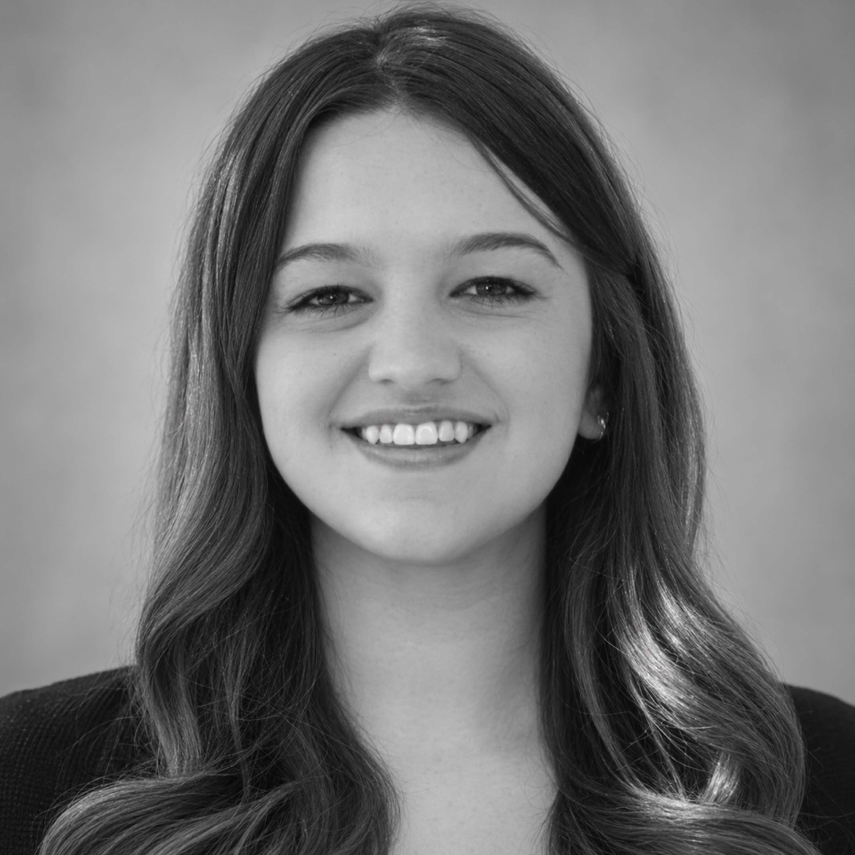 A black and white headshot of a woman with long hair smiling