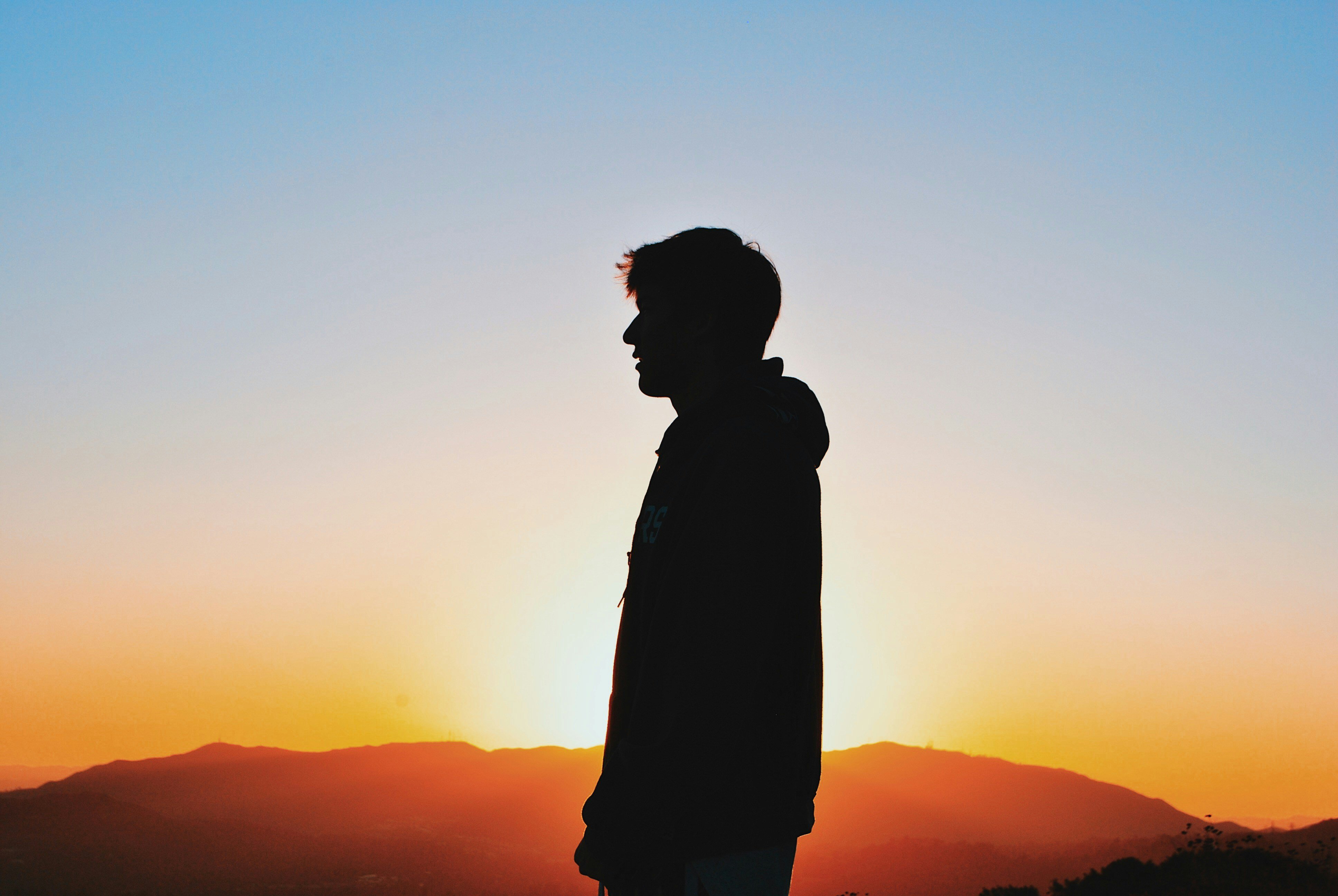 A silhouette of a man standing on a mountain at sunset