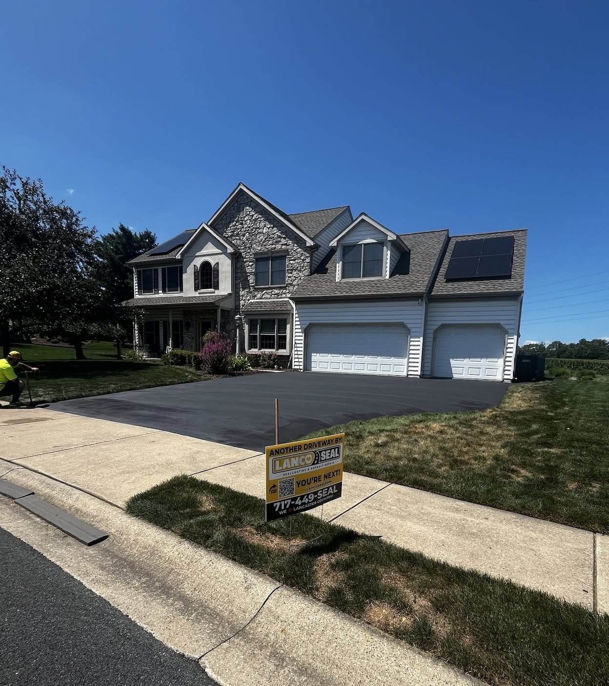A newly paved driveway with a sign advertising a local paving company
