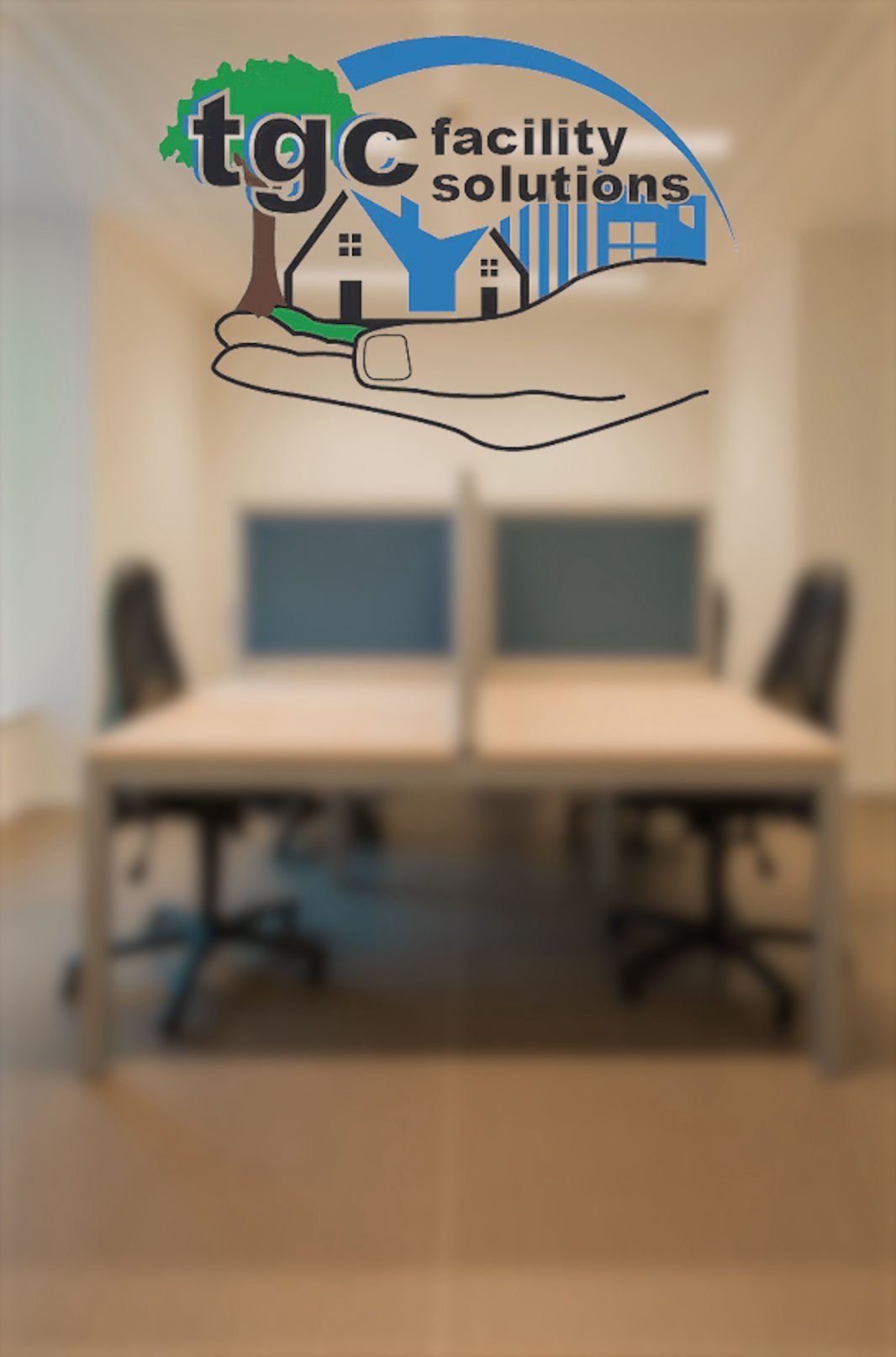 TGC Facility Solutions logo with a hand holding a house and tree, displayed on a glass wall in an office