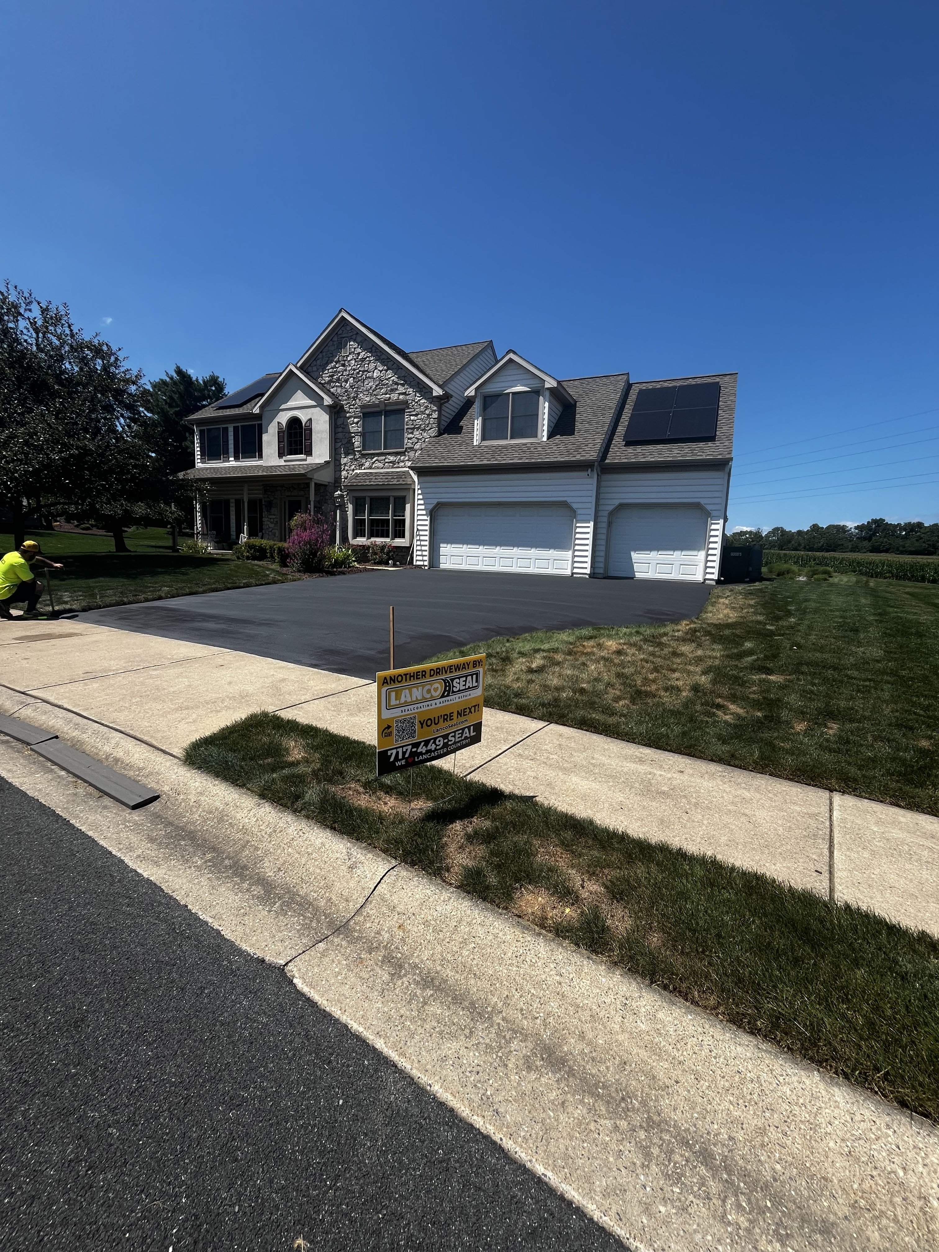 A driveway being repaved with a sign for Lancopo Seal in front of a house