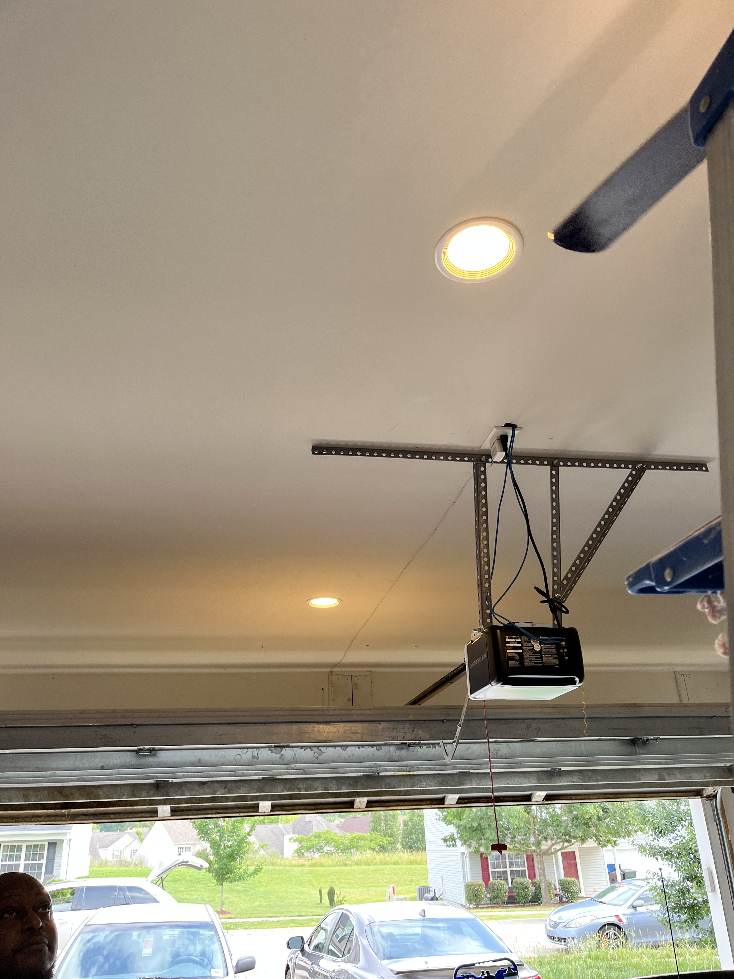 A garage with a ceiling-mounted garage door opener and a person standing in the foreground