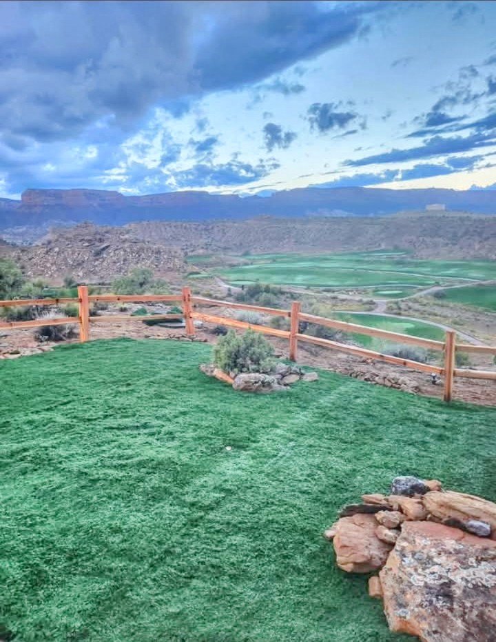 Aerial view of a golf course with a lush green lawn and a wooden fence
