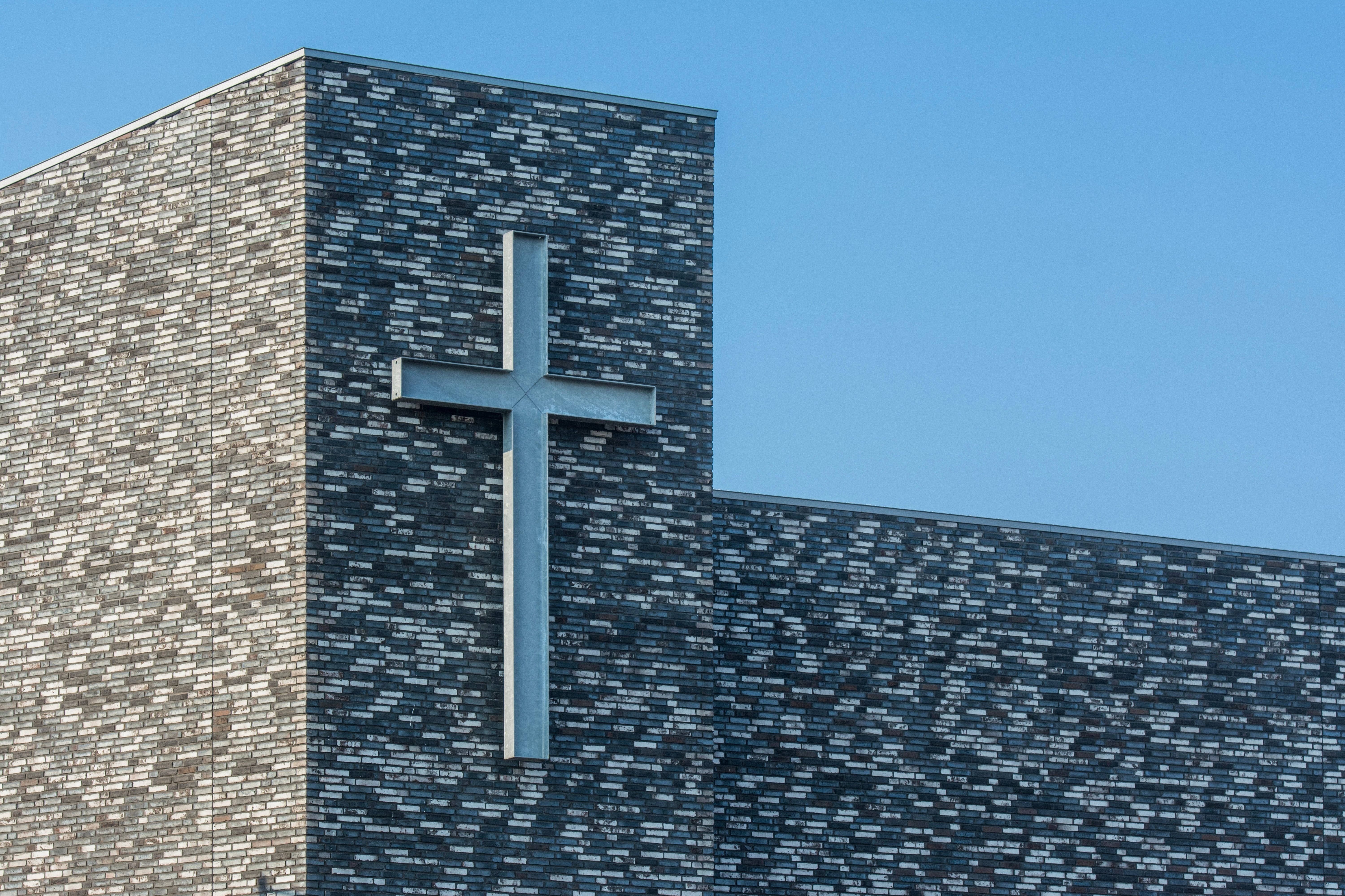 A modern church building with a large cross on the side, under a clear blue sky