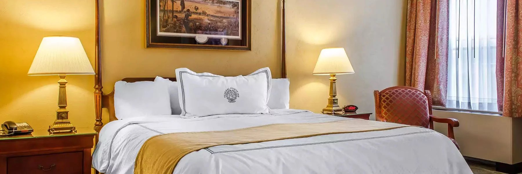 A luxurious hotel room with a bed, lamps, and a chair by the window