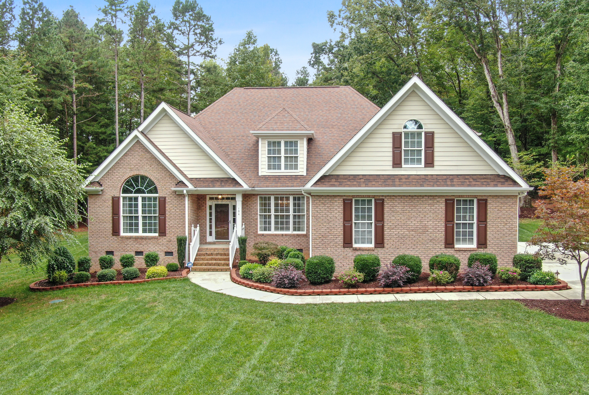 A brick home with white trim surrounded by mature trees in McSherrystown, PA