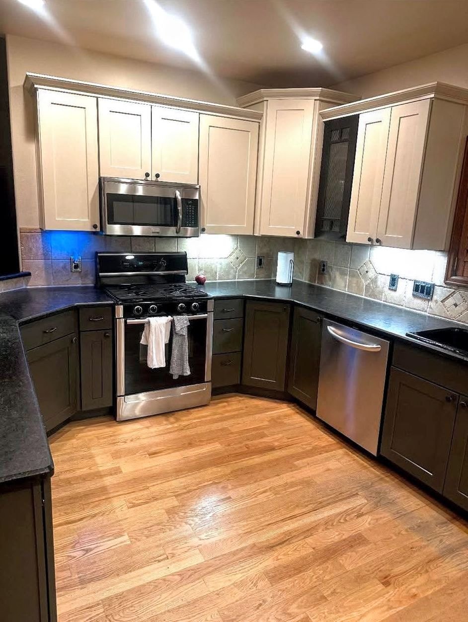 A modern kitchen with wooden floors, white cabinets, and stainless steel appliances