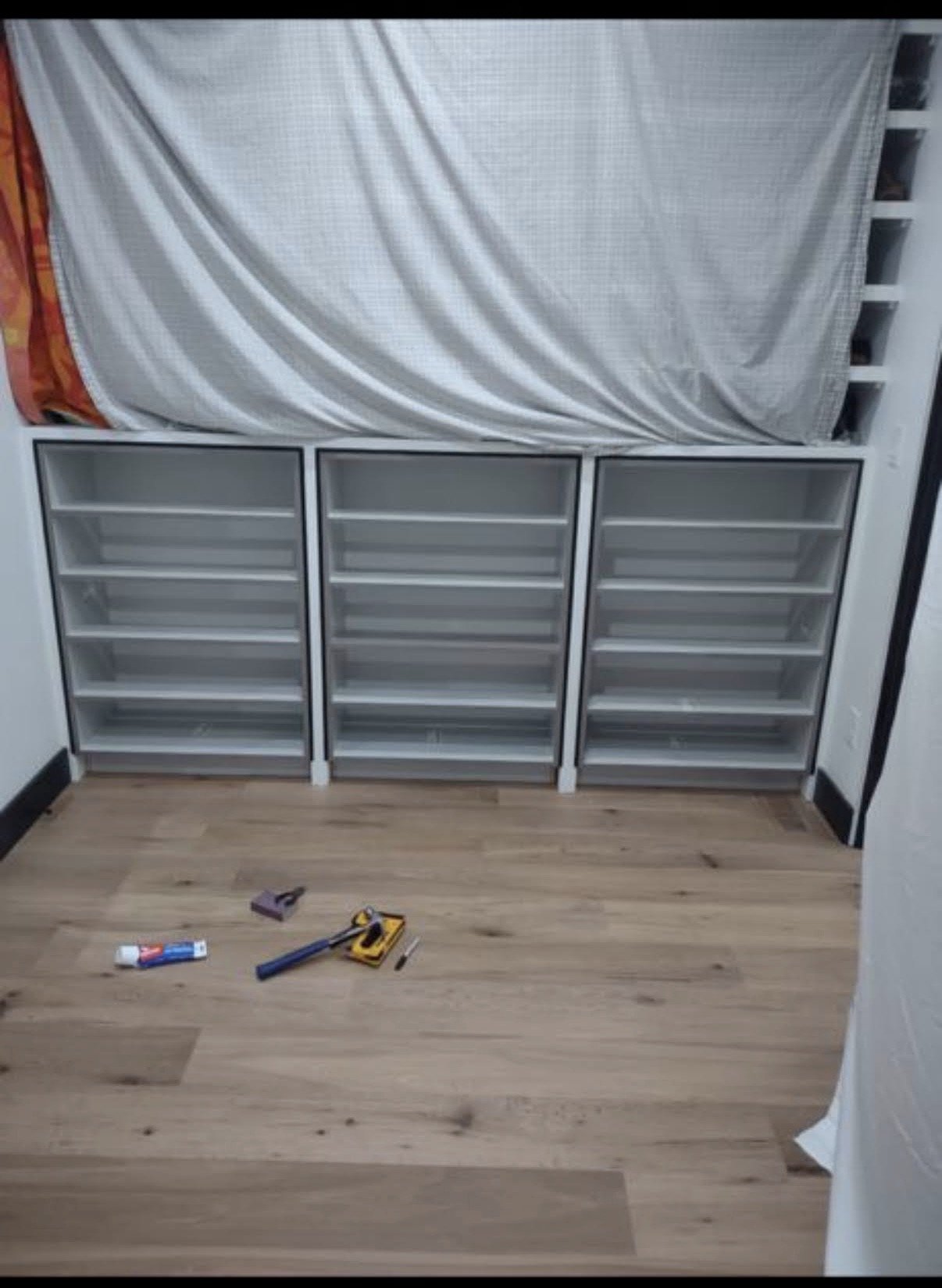 Three empty glass shelves with a white curtain in the background