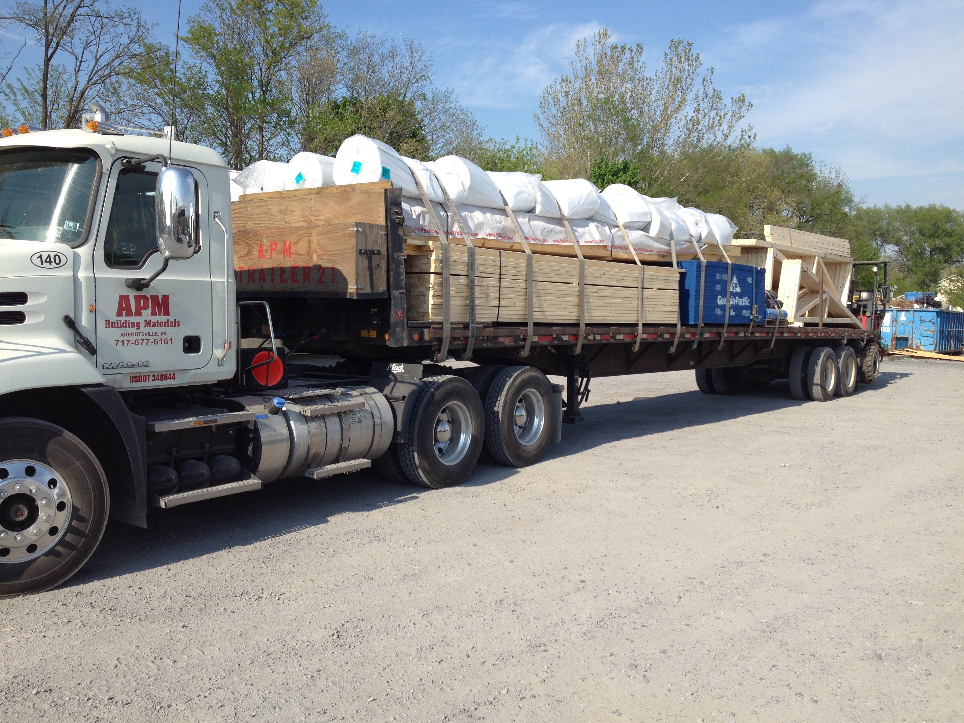 APM Building Materials truck loaded with building supplies parked in a lot