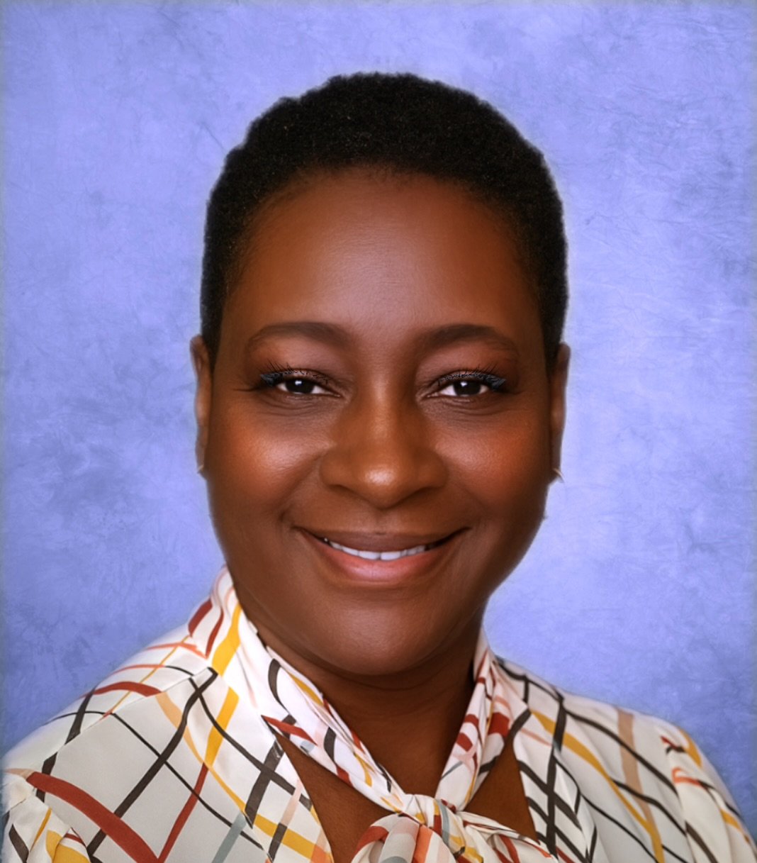 Cherrice Lewis, a smiling nurse in a patterned shirt, standing against a blue background.