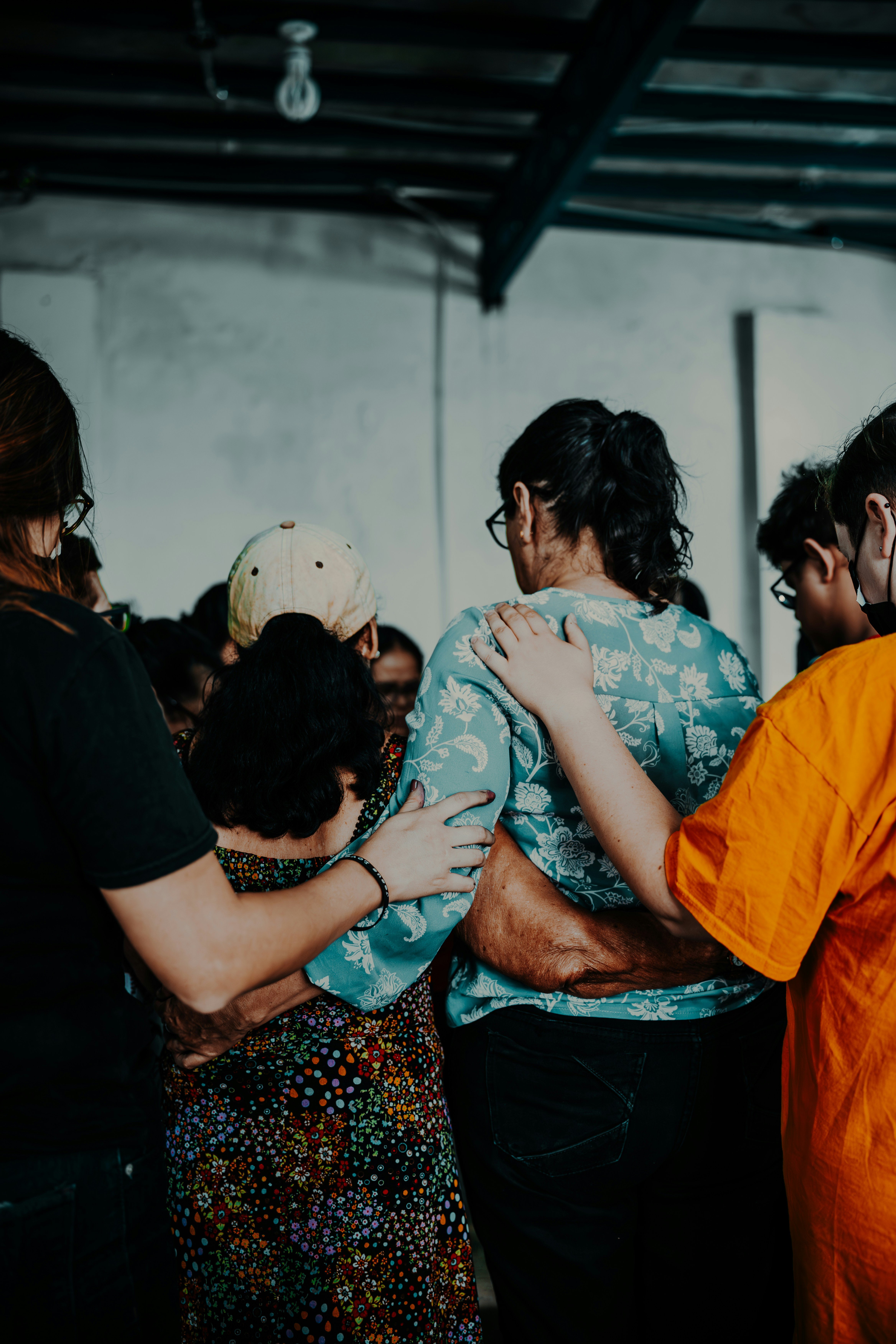 A group of people standing close together, possibly in a church, with their arms around each other.